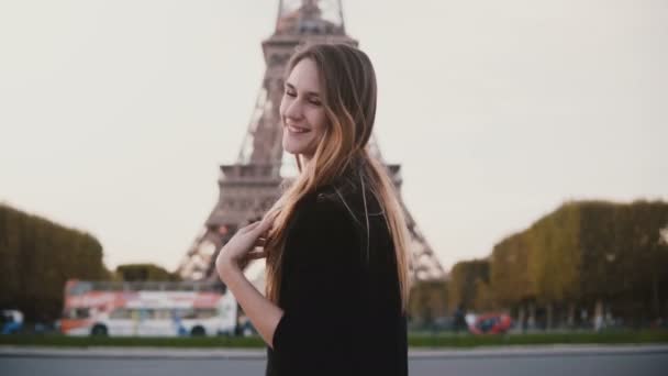 Feliz hermosa mujer de pie cerca de la torre Eiffel en París, Francia. Chica sonriendo y enviando el beso golpe a la cámara . — Vídeos de Stock