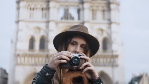 Mladá krásná žena stojící poblíž Notre Dame v Paříži a fotografování na retro film fotoaparát.