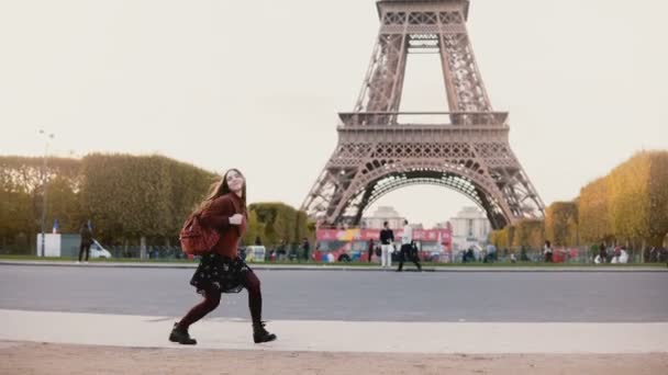 Joven mujer elegante corriendo y saltando cerca de la torre Eiffel en París, Francia. Adolescente feliz de ver la famosa vista . — Vídeo de stock