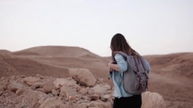 Kadın dağ damla yürür. Ağır çekim. Çöl kanyonun kenarında genç turist kız. Rüzgarda saç. İsrail.