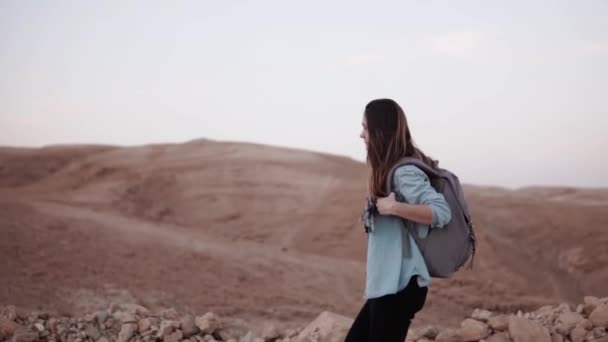Caucasian woman hiking in desert. Slow motion. Tourist girl wanders on desert canyon edge smiling happy. Israel summer. — Stock Video