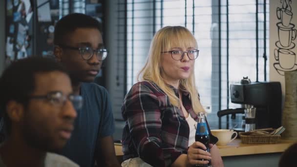 Multi-ethnic serious students at a meeting. Slow motion. Serious Caucasian girl in glasses listens carefully with drink — Stock Video