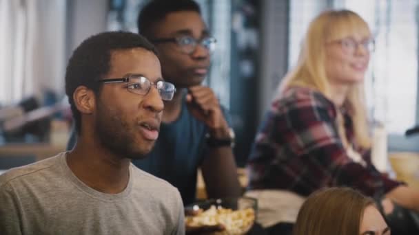 I giovani multietnici guardano la TV a casa. Diversi amici discutono di film sul divano insieme. Tempo di legame. Pubblicità . — Video Stock