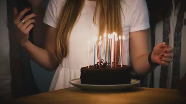 Persone che ballano intorno alla torta di compleanno con le candele. Gli amici festeggiano insieme. La ragazza con la camicia bianca tiene una torta. Festa. 4K — Video Stock