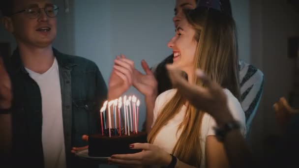 Beautiful woman makes a wish and blows on candles. Diverse multi ethnic group celebrate birthday party together. 4K. — Stock Video