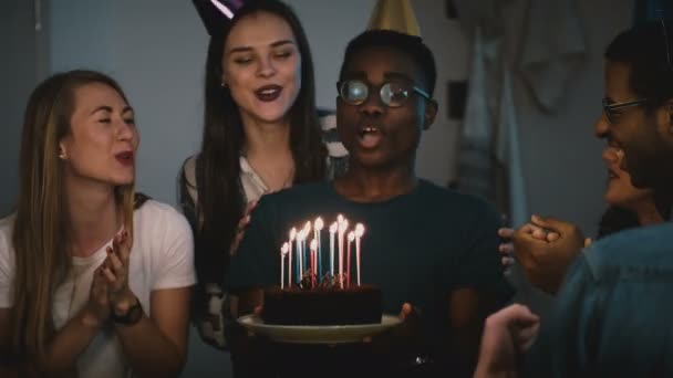 African American guy makes wish, blows on candles. Happy multi ethnic friends share birthday party celebration. 4K. — Stock Video