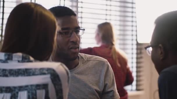Jonge African American man praat aan vrienden. Multi-etnische gezond kantoor. Casual diverse groepsgesprek met popcorn — Stockvideo