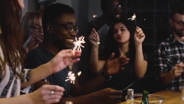 Mixed race young people dance with Bengal lights. Slow motion. Birthday celebration house party. Happiness emotion. — Stock Video