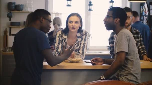 Různorodá skupina přátel na house party. Neformální rozhovor u kuchyňského stolu. Více etnických mladých lidí. 4k. — Stock video