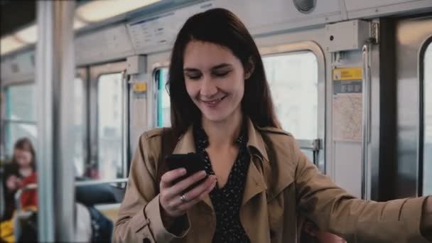 Mujer atractiva usando teléfono inteligente en el coche del metro. Hermosa chica europea joven en la red social aplicación web en línea. 5G. 4K — Vídeos de Stock