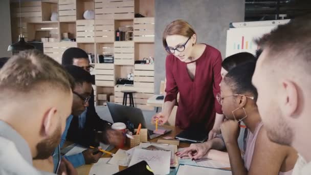 Жіноча команда лідера пояснює нові завдання для співробітників. Щасливі багатоетнічне колег мозковий штурм в офісі зустрічі 4 к. — стокове відео