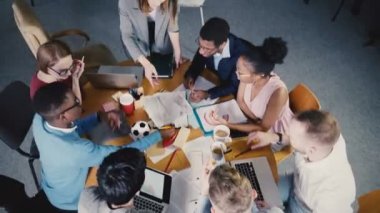 Üstten Görünüm çok ırklı yaratıcı ekibi beyin fırtınası trendy modern coworking ofisinde. Kadın patron neden toplantı 4k.