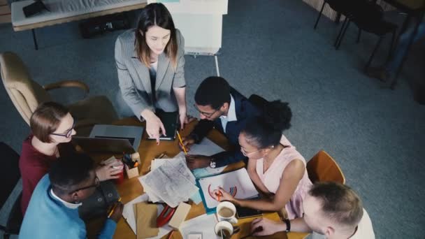 Top ver colegas de carreras mixtas que trabajan junto a la mesa en la oficina moderna de moda. Jefa mujer liderando diversa reunión de equipo 4K — Vídeos de Stock