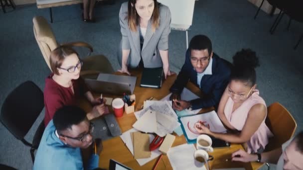 Travail d'équipe en vue supérieure au bureau de l'entreprise de développement. Équipe créative multiethnique discutant du marché immobilier à la table 4K 