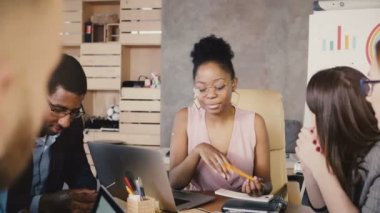 Afrikalı-Amerikalı kadın Yöneticisi office toplantısında. Mutlu çok ırklı meslektaşları modern pazar eğilimleri tartışmak. 4k.