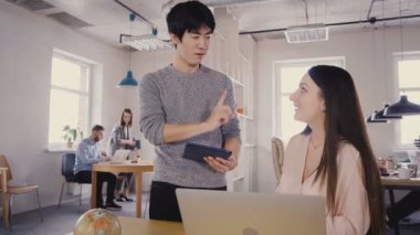 Modern ofis içinde çok ırklı meslektaşları konuşmak. İş güzel beyaz kız 4 k ile tartışırken mutlu Asya delikanlı.