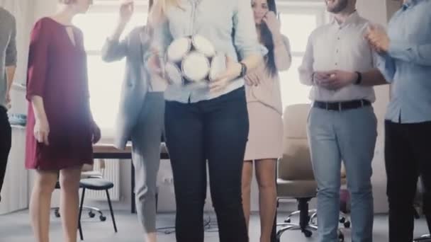 Les employés de bureau heureux tiennent une activité physique. Jeunes collègues multiethniques célébrant, jouer avec le ballon de football 4K 