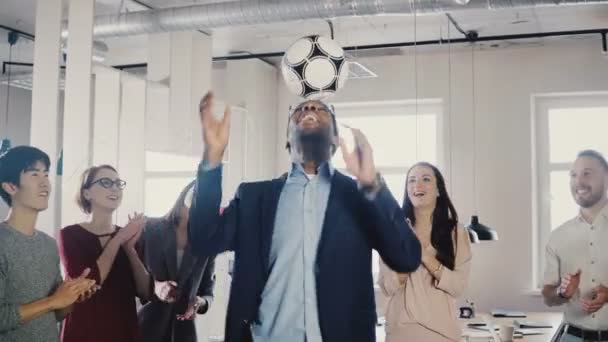 Счастливый афро-американский генеральный директор жонглирует головой. Мультиэтнические бизнесмены отмечают успех в офисе 4K . — стоковое видео