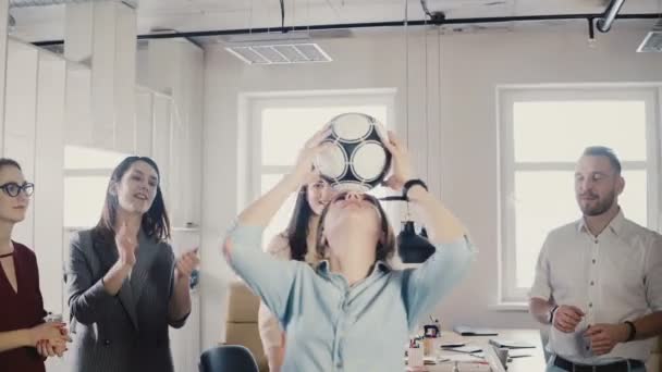 Chica caucásica hace malabares de fútbol en la cabeza en la oficina. Felices negocios multirraciales celebran éxito laboral aplaudiendo 4K . — Vídeos de Stock