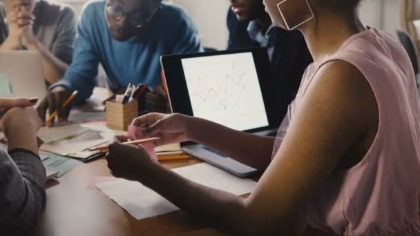 Woman lays sticky note, holds pencil at meeting. Young multiethnic creative group brainstorming in modern office 4K. — Stock Video