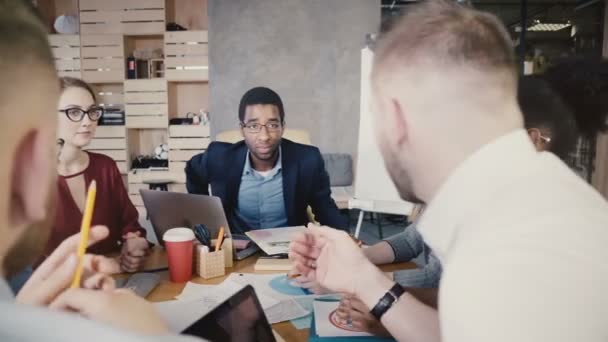 African American team leader at office meeting. Young multiethnic business people brainstorm in trendy coworking 4K. — Stock Video