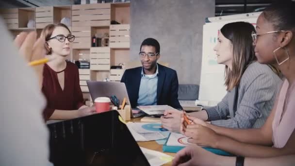 Colaboração empresarial no moderno escritório loft. Jovens felizes colegas multiétnicos start-up sorrindo, brainstorming 4K . — Vídeo de Stock