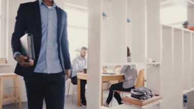 Çok ırklı mutlu iş adamları sohbet, el sallamak, gül. Genç siyah executive modern ışık ofisten 4 k yürür.