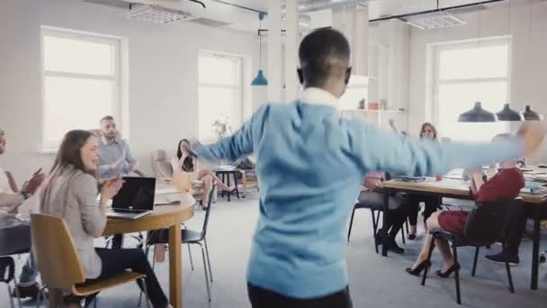 Caméra suit l'homme afro-américain entrer au bureau faisant danse joyeuse de succès, collègues multi-ethniques 4K . — Video