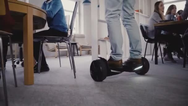 Young businessman using gyroscooter to move around the office. Confident business leader guides colleagues, close-up 4K. — Stock Video