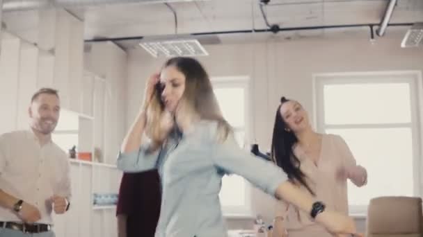 Счастливая девушка танцует лунный танец на корпоративной вечеринке. Мультиэтнические сотрудники танцуют вместе, празднуя успех бизнеса 4K — стоковое видео