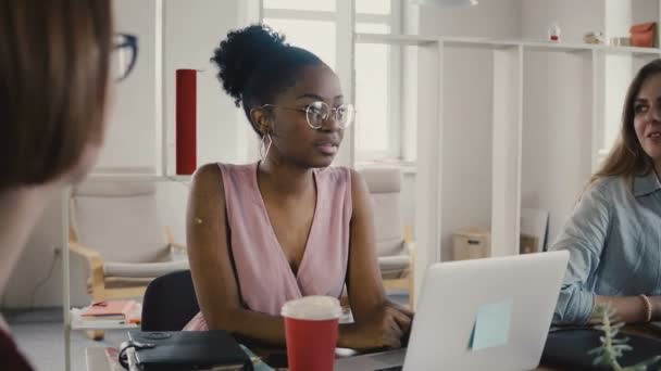 Empregada afro-americana feliz sentada à mesa na reunião de equipe. Trabalho em equipe multiétnica no escritório moderno 4K . — Vídeo de Stock