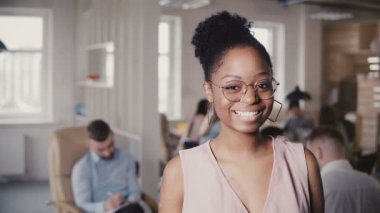 Kamera arka planda loft office 4 k bakarak güzel genç Afro-Amerikan başarılı işkadını, portresi.
