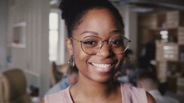 Mutlu gülümseyen Afro-Amerikan şirketin CEO'su, modern loft office arka plan 4 k kamerada bakarak yakın çekim portre.