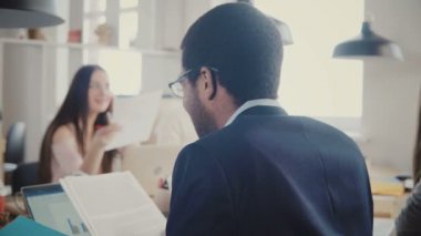 Belgeleri çok ırklı ofis toplantı, laptop 4 k diyagramlar aracılığıyla okuma görünümü Afrikalı-Amerikalı iş adamı geri.