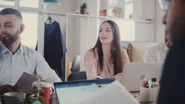 Щасливі багатоетнічні ділові люди зустрічаються в офісі. Жінка-менеджер дає документи співробітникам на модному робочому місці 4K . — стокове відео
