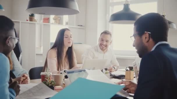 La entrenadora de negocios europea motiva al equipo por la mesa. Hermosa mujer jefe conduce mixta carrera oficina reunión 4K . — Vídeo de stock