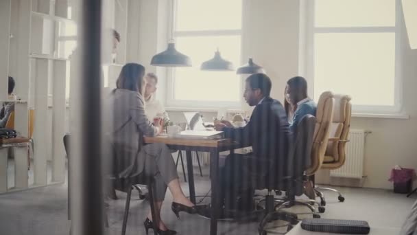 Dolly schot van teamwork aan loft moderne kantoor tafel. Multi-etnisch zakenmensen samenwerken, bespreken markt bij voldoen aan 4k. — Stockvideo