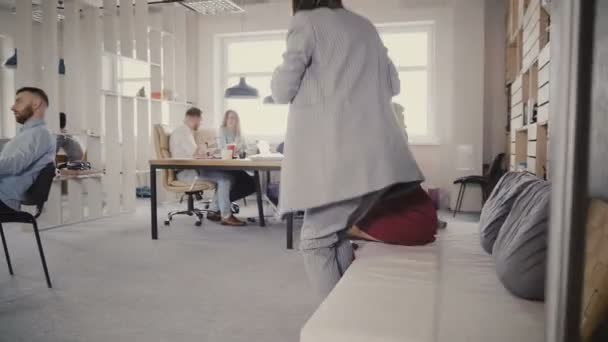 2 つの女性の同僚のドリー ショット オフィス ソファから立ち上がって、近代的なオフィスに徒歩します。ガラス貫通 4 k 表示します。. — ストック動画