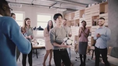 Asya adam futbol kafa ofiste tutmak çalışır. Mutlu karışık etnik işçiler oynarken eğlenceli bir spor oyun yavaş hareket.