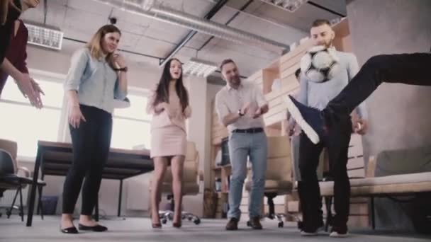 Multiethnic office colleagues play with football during break. Happy employees hold casual physical activity slow motion — Stock Video