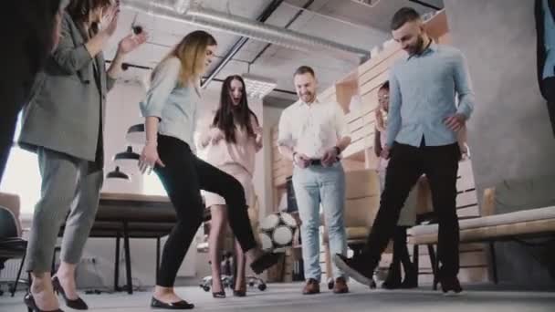 Young office employees play with football during break. Casual workers enjoy healthy workplace atmosphere slow motion. — Stock Video