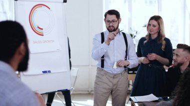 Profesyonel genç pozitif iş adamı ofis konferansında çeşitli takımlarla aktif tartışmalara öncülük ediyor..