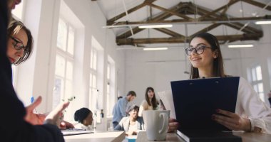 Gözlüklü, kendine güvenen genç takım lideri kadın modern ofisteki çok ırklı meslektaşlarına talimat veriyor..