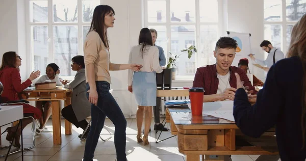 Camera moves left along modern loft office, happy multiethnic business people enjoy working at healthy trendy workplace.