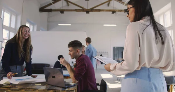 Elegante joven confiada líder de equipo mujer en gafas dando instrucciones a colegas multiétnicos en la oficina moderna . — Foto de Stock