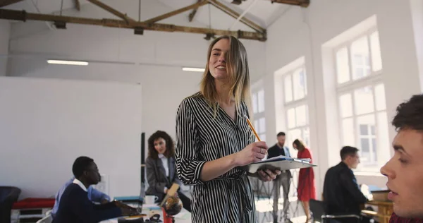 Câmera segue líder feminina loira de sucesso motivando funcionários multiétnicos no escritório da moda loft. Local de trabalho saudável — Fotografia de Stock