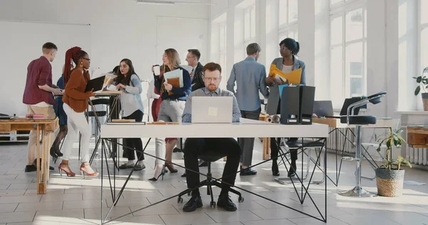 Cámara se acerca a los agotados jóvenes empresarios arrojando documentos de papel en el aire en la concurrida mesa de oficina moderna RED EPIC . — Foto de Stock