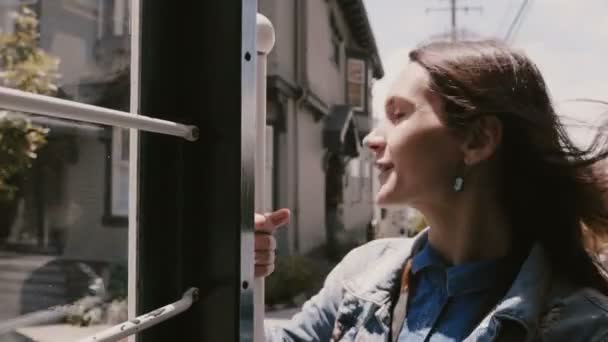 Close-up vrolijke jonge vrouwelijke toerist genieten van prachtige rit in iconische San Francisco kabelbaan met wind waait in het haar. — Stockvideo