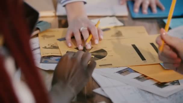 Close-up mixte analyse d'entreprise les travailleurs de l'entreprise collaborent sur une grande table de bureau avec des feuilles de diagramme imprimées . — Video