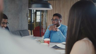 Yakışıklı Afrikalı-Amerikalı genç Yöneticisi iş modern ofis 4 k takım toplantıda çok ırklı meslektaşları ile tartışıyor.